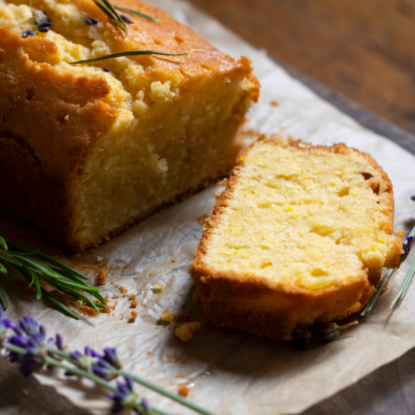 a slice from a loaf of Lavender Sour cream Pound Cake sits on a cutting board, with sprigs of lavender.